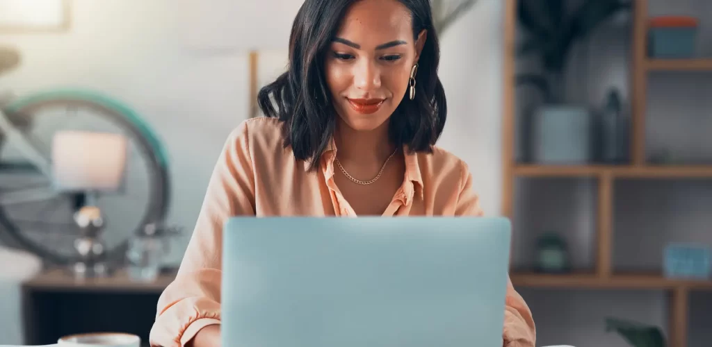 Woman working on laptop online, checking emails and planning on the internet while sitting in an office alone at work. Business woman, corporate professional or manager searching the internet